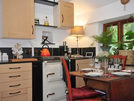 A kitchen with wooden cabinets and a dining table set at Coach House in Camelford
