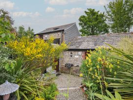 A garden with plants and a building at Coach House Camelford