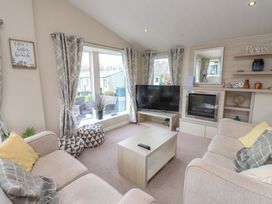 A living room with a television and seating area at 56 The Stables
