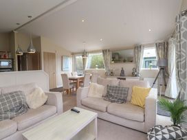 A living room with sofas, a coffee table, and a dining area at 56 The Stables