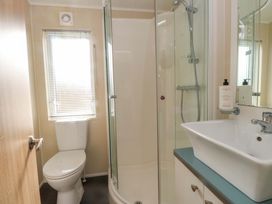 A bathroom featuring a shower, toilet, sink and window at 56 The Stables