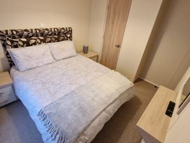 A bedroom with a bed and nightstand at 56 The Stables near Pwllheli