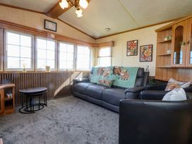 A living room with a sofa and large windows at Caravan at Argraig Llanrhyddlad near Cemaes Bay