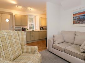 A living room with an armchair and a kitchen area at Bobtail Cottage in Kendal