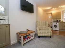 A living room with a television and armchair at Bobtail Cottage in Kendal