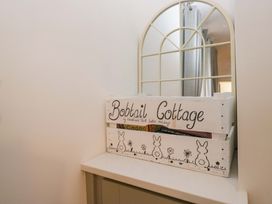 A crate with books next to a mirror at Bobtail Cottage in Kendal
