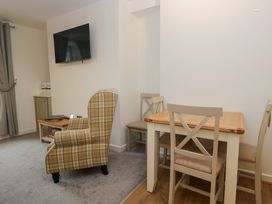 A living room with an armchair and dining table at Bobtail Cottage in Kendal