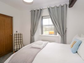 A bedroom with a bed and window at Bobtail Cottage in Kendal