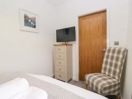 A bedroom with a television and chair at Bobtail Cottage in Kendal