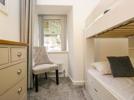 A bedroom with a bunk bed and a chair at Bobtail Cottage in Kendal