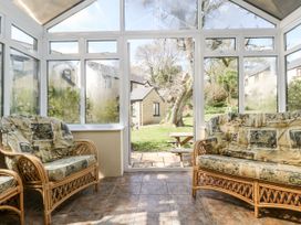 A conservatory with wicker sofas looking out to the garden at Oak Cottage in Falmouth