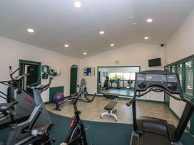 A gym with exercise equipment and a mirror at Oak Cottage in Falmouth