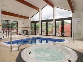 An indoor pool area with a hot tub and swimming pool at Oak Cottage in Falmouth