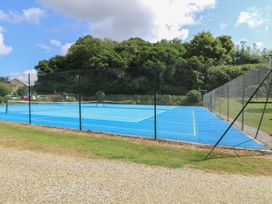 A tennis court with a net and surrounding fence at Oak Cottage in Falmouth