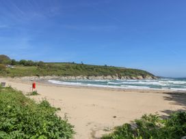 A beach with sand and sea waves at Oak Cottage in Falmouth