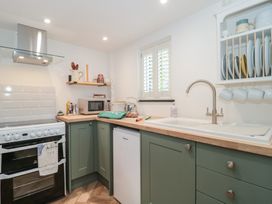A kitchen featuring an oven, microwave, sink, and dishes at Ruby’s Den Ashton Keynes