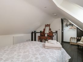 A bedroom with a bed and a mirror at Ruby’s Den Ashton Keynes