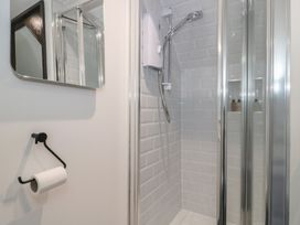 A shower with a mirror and toilet paper holder at Ruby’s Den Ashton Keynes