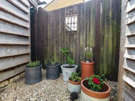 A garden with potted plants and a wooden fence at Ruby’s Den Ashton Keynes