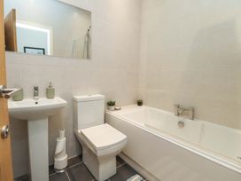 A bathroom with a bath tub, toilet, sink, and mirror at Flat 2, Dorstan in Carnforth