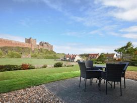 A garden with a table and chairs overlooking a castle at Northrawe Bamburgh