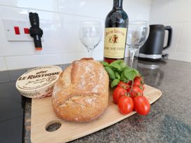 A kitchen countertop with bread, cheese, wine, tomatoes and glasses at Masons Place Whitby