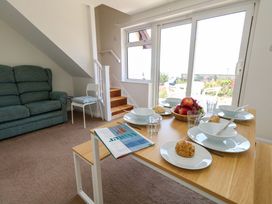 A dining room with a table set for meals and a sofa at 32 Bowleaze Coveway in Weymouth
