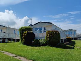 A mobile home with grass and a pathway at Reighton Sands Holiday Park - Holiday Accommodation 17652 Filey