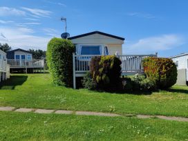 An outdoor view of a caravan surrounded by grass and bushes at Reighton Sands Holiday Park - Holiday Accommodation 17652, Filey