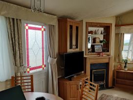 A living room with a tv and fireplace at Reighton Sands Holiday Park - Holiday Accommodation 17652, Filey