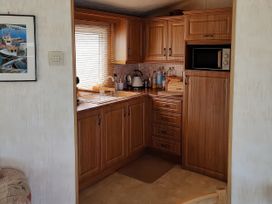 A kitchen with wooden cabinets and a sink at Reighton Sands Holiday Park - Holiday Accommodation 17652, Filey