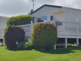 A house with a deck and bushes at Reighton Sands Holiday Park - Holiday Accommodation 17652, Filey