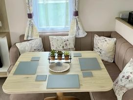 A dining area with a table and cushions at Static Caravan Hoburne Devon Bay, Paignton