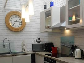 A kitchen with a clock, sink, microwave, coffee maker, and wine bottle at House - Sleeps 7 - Garden - Pets Ok - Parking in Torquay