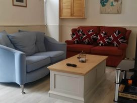 A living room with blue armchair and red sofa at House - Sleeps 7 - Garden - Pets Ok - Parking in Torquay
