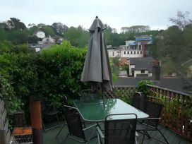 A garden with a table and chairs under an umbrella at House - Sleeps 7 - Garden - Pets Ok - Parking in Torquay