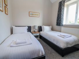 A bedroom with two single beds and a nightstand at Elwy Cottage in St Asaph