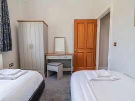 A bedroom with two beds, wardrobe, mirror, and desk at Elwy Cottage in St Asaph