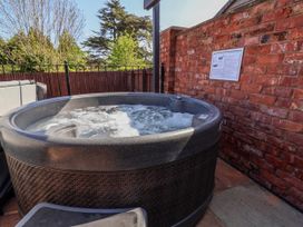 A hot tub with water and a sign in an outdoor area at Elwy Cottage St Asaph