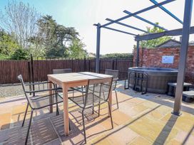 An outdoor area with a table, chairs, and a hot tub at Elwy Cottage in St Asaph