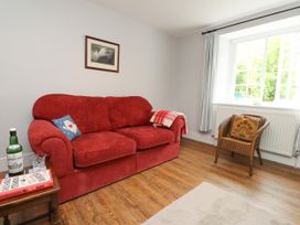 A living room with a red sofa and coffee table at 3 Tre Felin in Llandygai near Bangor