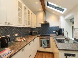 A kitchen with cabinets, a sink and kitchen appliances at 3 Tre Felin in Llandygai near Bangor