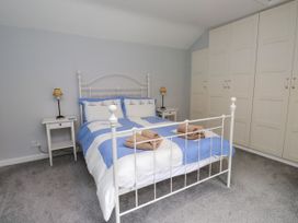 A bedroom with a bed, bedside table, and wardrobe at 3 Tre Felin in Llandygai near Bangor