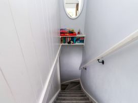 A staircase with a bookshelf and a mirror at 3 Tre Felin in Llandygai near Bangor