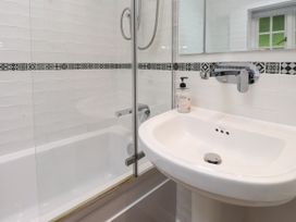 A bathroom with a bathtub, shower, sink and mirror at 3 Tre Felin in Llandygai near Bangor