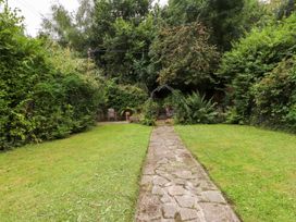 A garden with a stone pathway leading to a seating area at 3 Tre Felin in Llandygai near Bangor