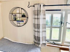 A corner with a shelf, plants, and curtain at Cwt Tyddyn Shepherd's Hut in Corwen