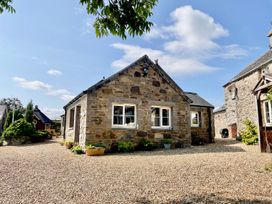 A stone cottage with a gravel driveway and plant pots at Cwt Tyddyn Shepherd's Hut in Corwen