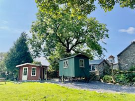 A shepherd's hut and a red cabin outside at Cwt Tyddyn Shepherd's Hut in Corwen