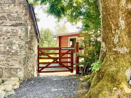 An outdoor view of a wooden gate and stone wall at Cwt Tyddyn Shepherd's Hut in Corwen